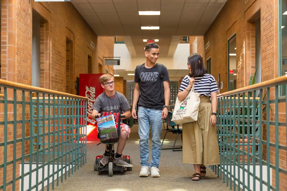 Three students moving through a hallway