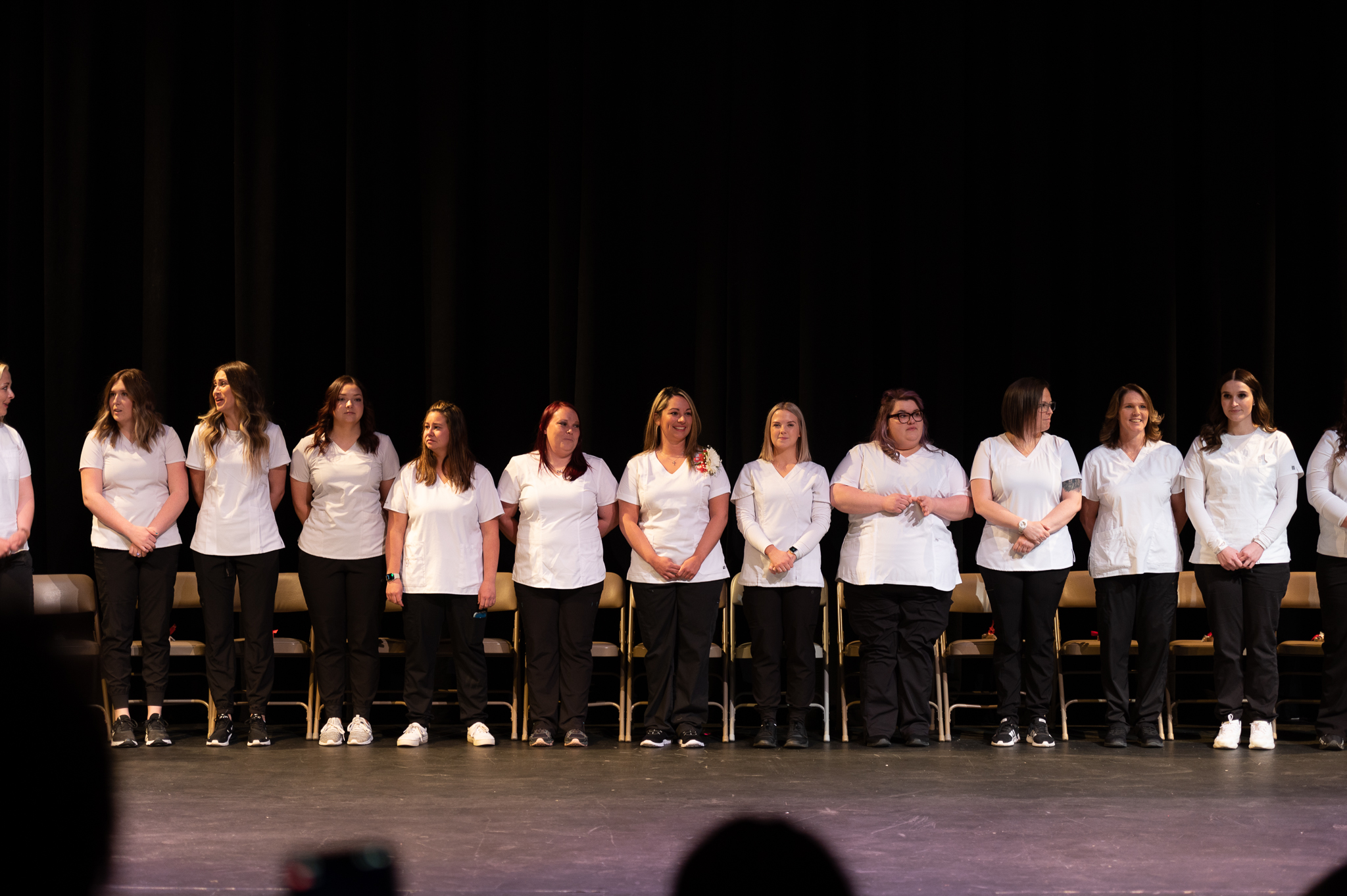 Nursing graduates standing on stage during pinning ceremony 