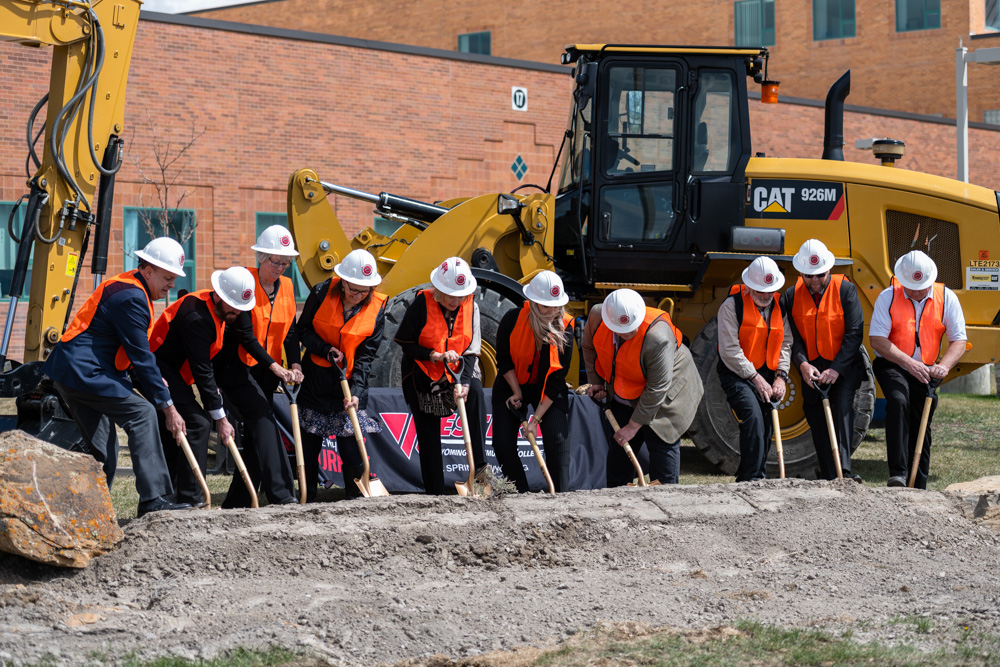 Group photo of Western Board of Trustees, Dr. Kim Dale President, VP Administrative Services Burt Reynolds, Nursing Chair Heidi Brown and Director of Facilities Chris Dever posing with golden shovels in hand digging at the construction site. 