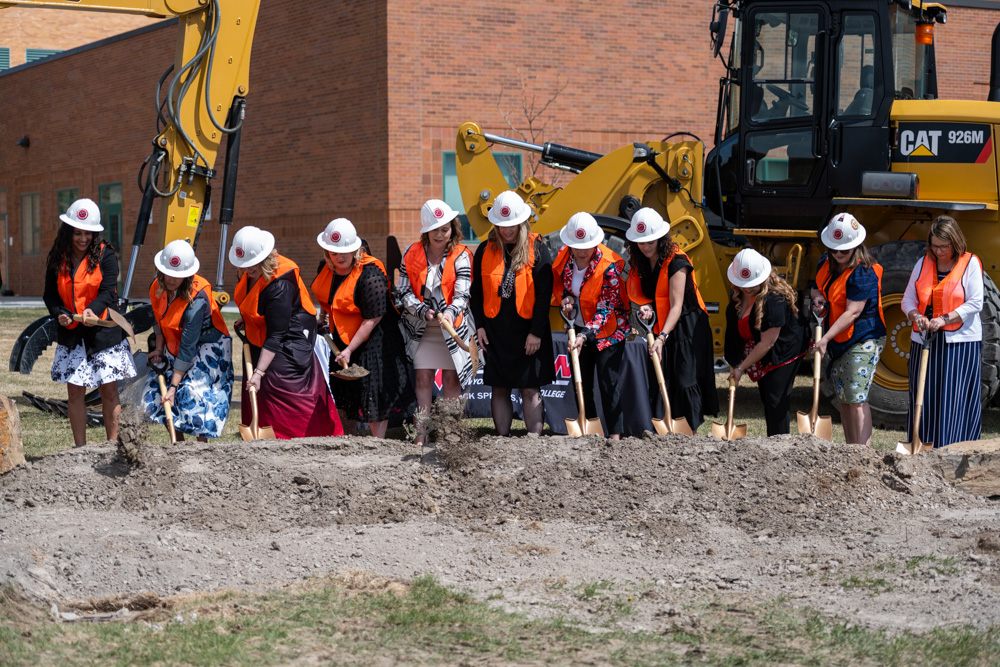 Group photo of Nursing faculty, staff and students posed with golden shovels digging at the construction site. 