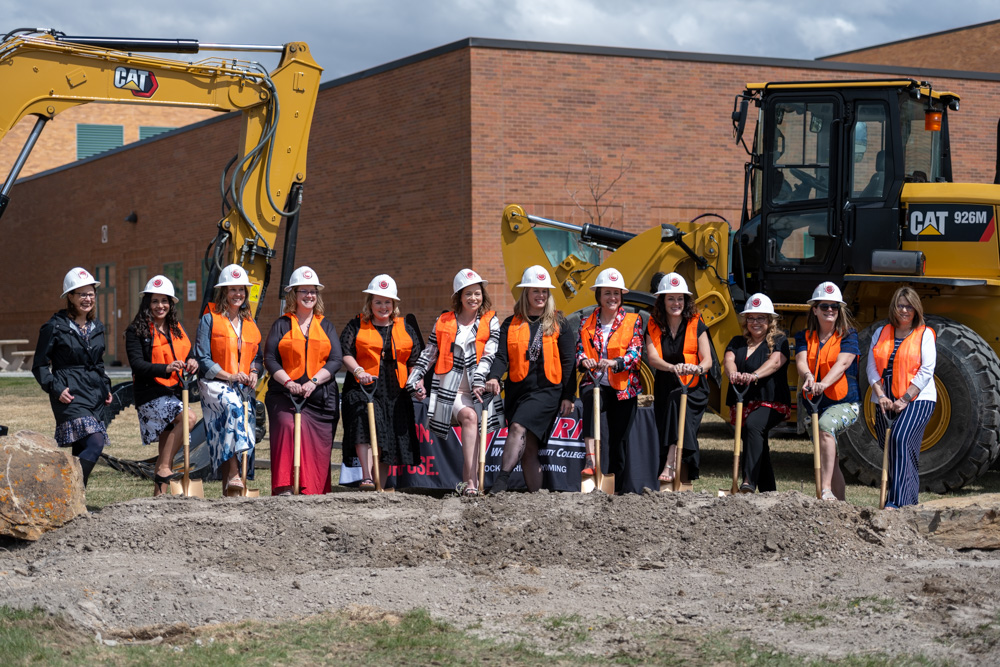Group photo of Nursing faculty, staff and students posed with golden shovels getting ready to dig at the construction site. 