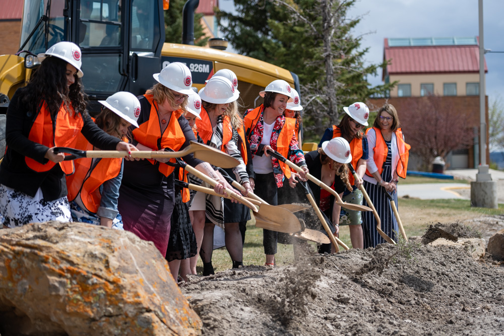 Group photo of Nursing faculty, staff and students posed with golden shovels digging at the construction site. 