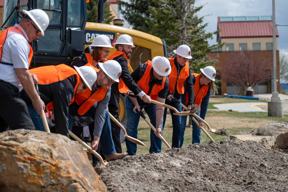 Group photo of project contractors, director of facilities Chris Dever, VP Administrative Services Burt Reynolds and Nursing Chair Heidi Brown digging wihh golden shovels at construction site. 