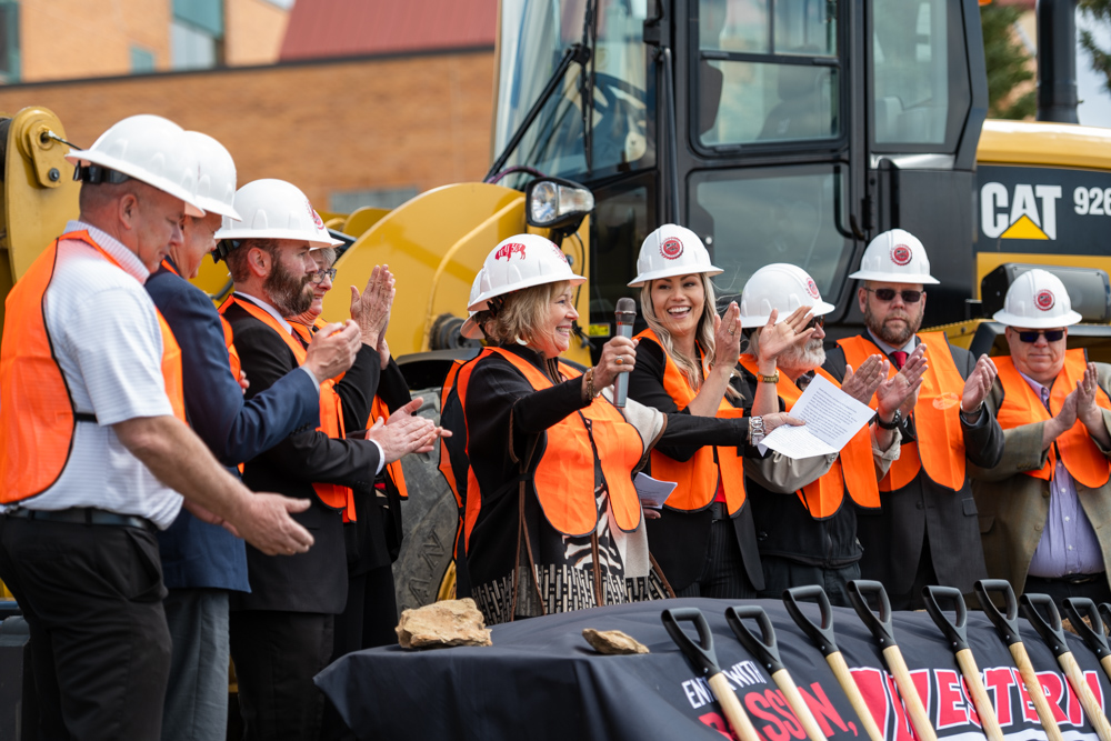 Group photo of Western Board of Trustees, Dr. Kim Dale President, VP Administrative Services Burt Reynolds, Nursing chair Heidi Brown and Director of Facilities Chris Dever posed in front of golden shovels at the construction site. 