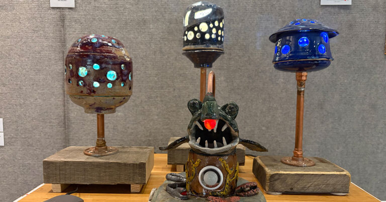A trio of lamps featuring unique designs, each mounted on wooden stands, displayed together on a simple surface.