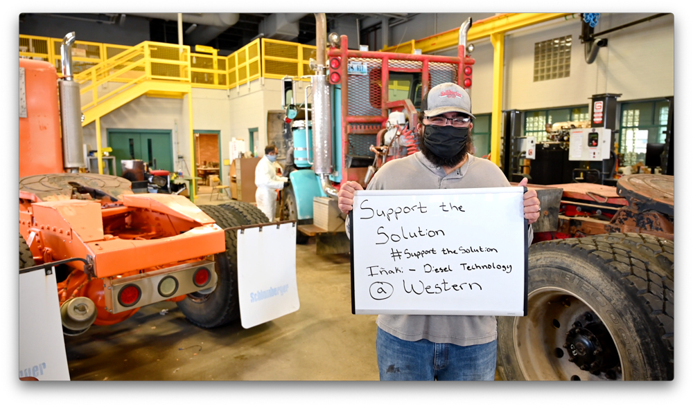 A diesel student holding a sign stating #SupportTheSolution