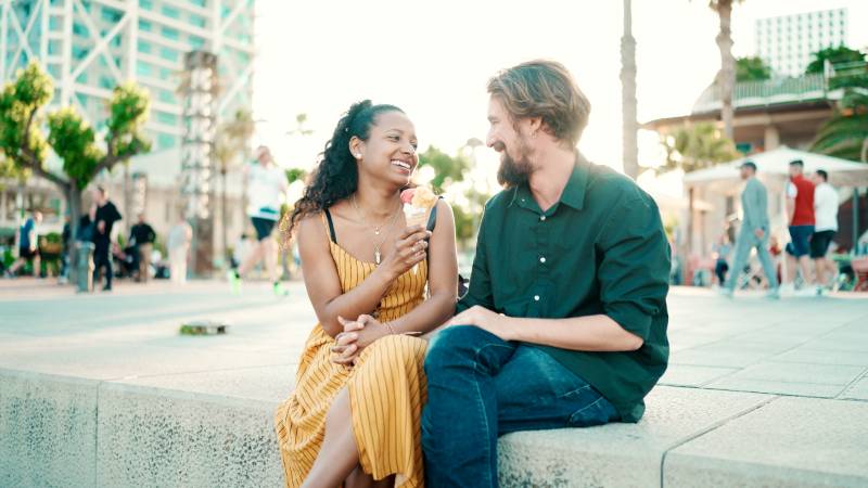 Closeup portrait of happy interracial couple eating ice cream in urban city background