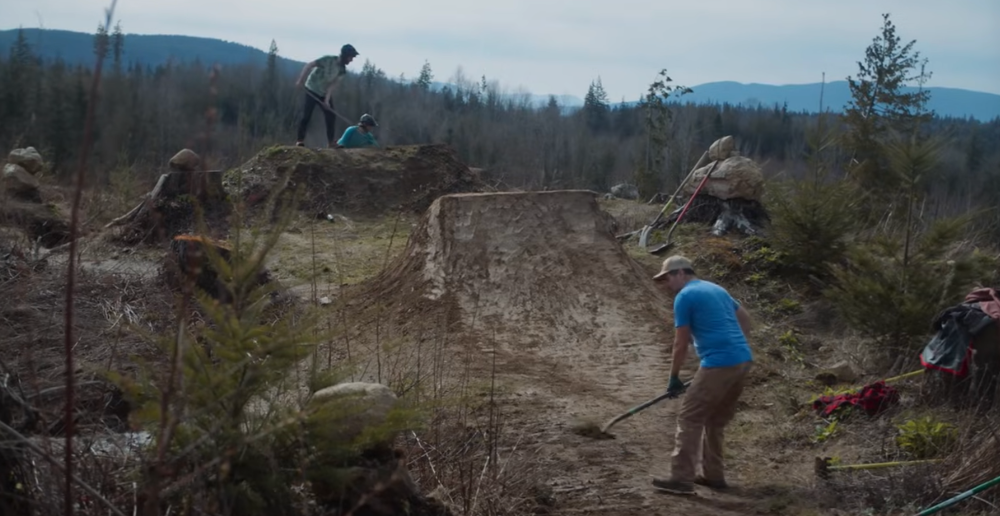 Mountain bike club working on jumps in logging forest area. 