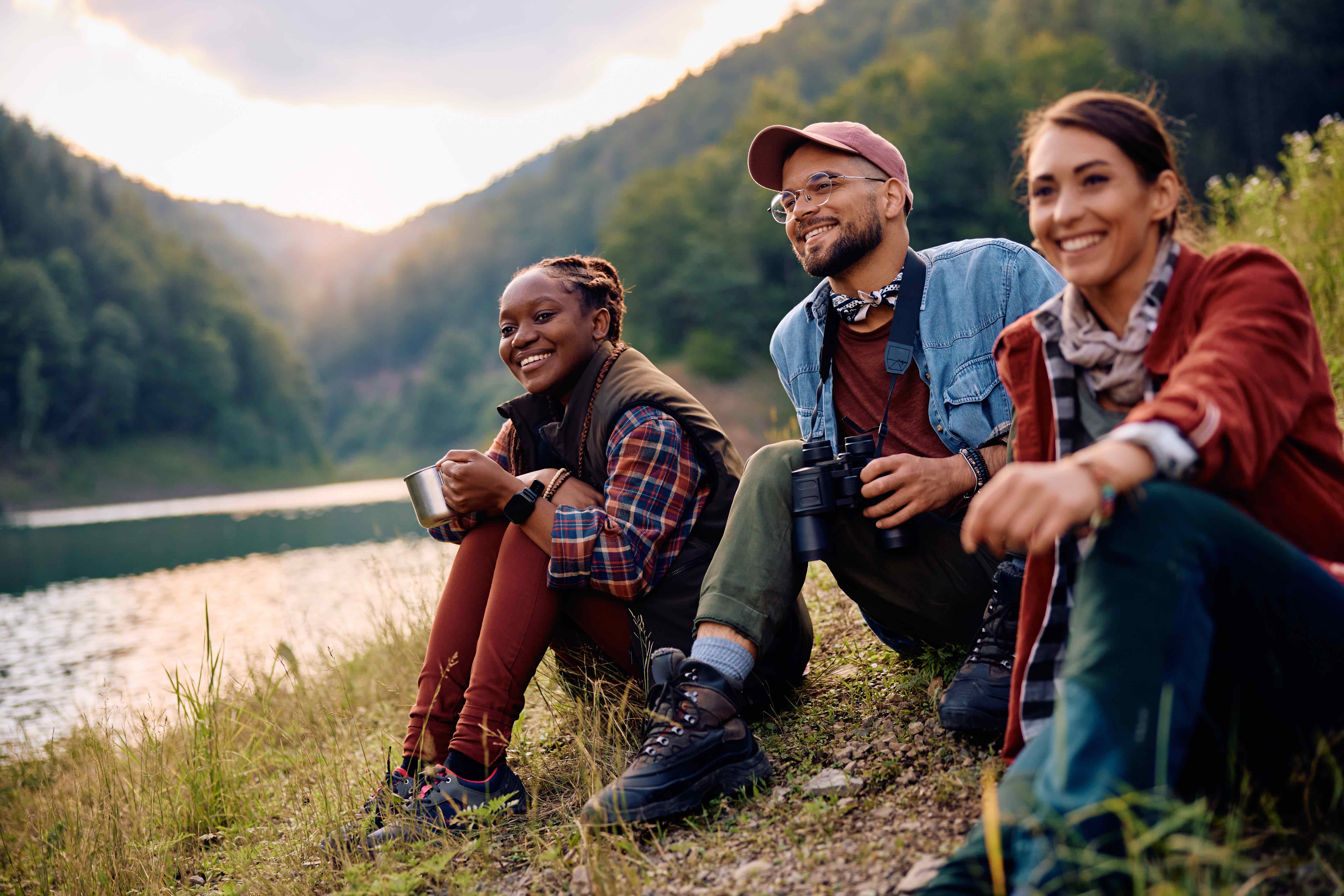 Two professors and a student sitting on the lake shore siteseeing.