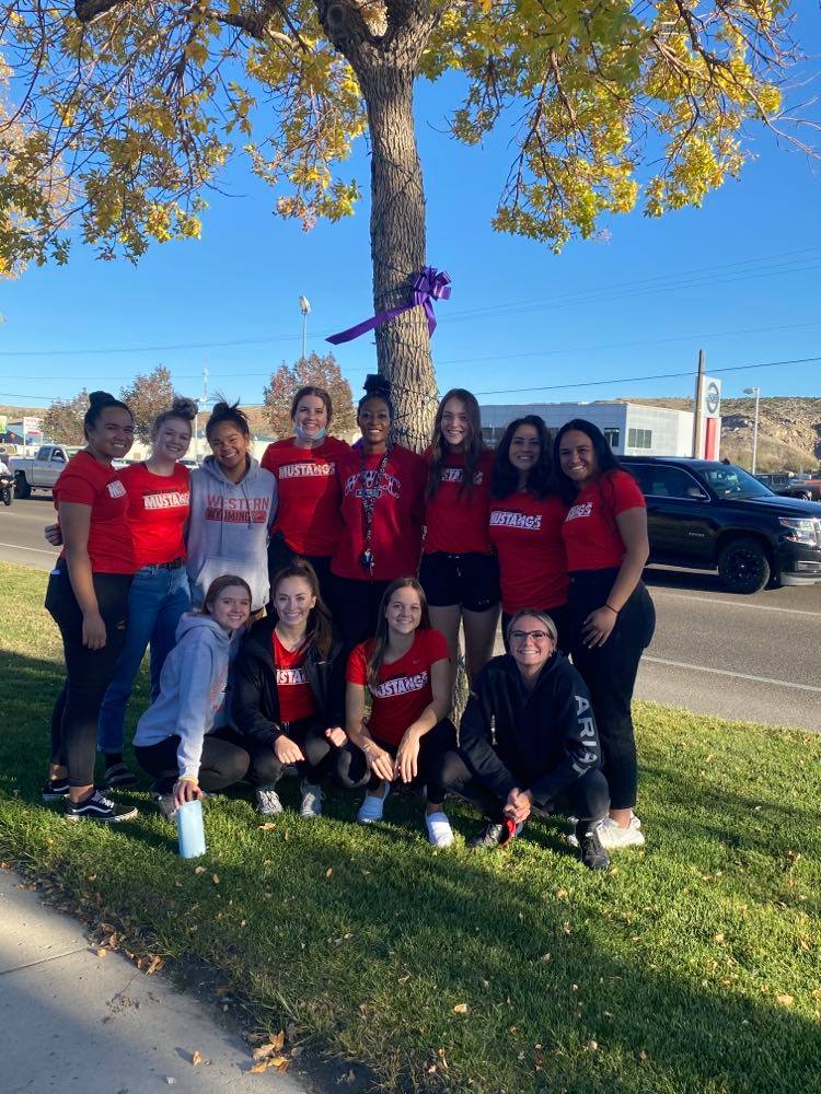 Mustang Volleyball team group shot near a decorated holiday tree. 